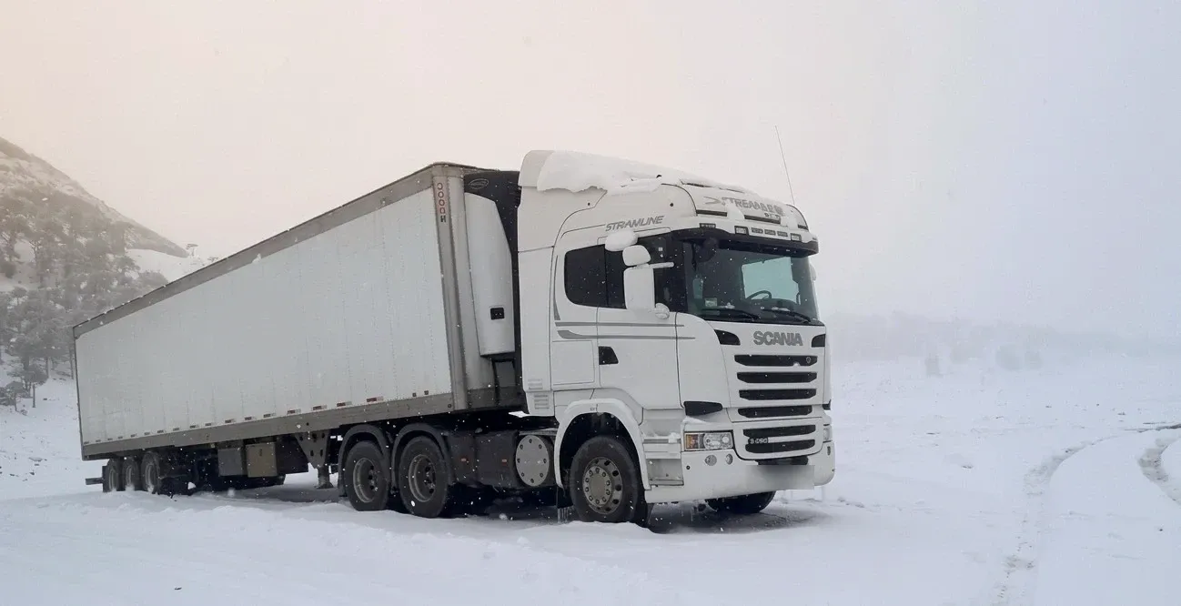 Camión refrigerado Solvex operando en la cordillera nevada, entre niebla y nieve.